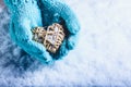 Female hands in light teal knitted mittens with entwined beige flaxen heart on a white snow background. St. Valentines Day concept Royalty Free Stock Photo