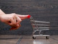 Female hands and a little empty trolley supermarket basket on the floor against the backdrop of a wooden wall Royalty Free Stock Photo