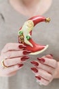 Female hands with long nails and red manicure hold a small statuette of Santa Claus Royalty Free Stock Photo