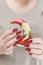 Female hands with long nails and red manicure hold a small statuette of Santa Claus Royalty Free Stock Photo