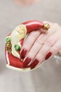 Female hands with long nails and red manicure hold a small statuette of Santa Claus Royalty Free Stock Photo