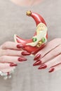 Female hands with long nails and red manicure hold a small statuette of Santa Claus Royalty Free Stock Photo