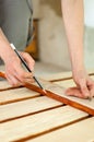 Female hands are making some marks on wooden plank for future holes using pencil for assembling bench, gender equality