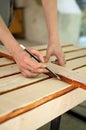 Female hands are making some marks on wooden plank for future holes using pencil for assembling bench, gender equality