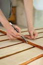 Female hands are making some marks on wooden plank for future holes using pencil for assembling bench, gender equality