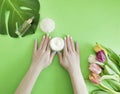 Female hands manicure, cosmetic cream,  creative tulip flower, monstera leaf on a colored background Royalty Free Stock Photo