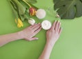 Female hands manicure, cosmetic cream moisturizing , monstera tulip leaf on a colored background Royalty Free Stock Photo