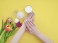 Female hands manicure, cosmetic cream, spring creative tulip flower, monstera leaf on a colored background Royalty Free Stock Photo