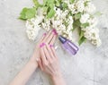 Female hands manicure cream healthy flower lilac on a gray concrete background