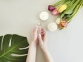 Female hands manicure, healthy lifestyle cosmetic cream, spring creative tulip flower, monstera leaf on a colored background Royalty Free Stock Photo