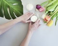 Female hands manicure, healthy lifestyle essen cream, spring creative tulip flower, monstera leaf on a colored background Royalty Free Stock Photo