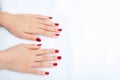 Female hands with manicure and red lacquer on a white table Royalty Free Stock Photo
