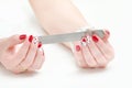 Female hands with manicure, red nail polish, nailfile in hand. W