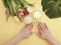 Female hands manicure, tulip flower hygiene creative cream summer , monstera leaf on a paper colored background Royalty Free Stock Photo