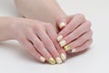 Female hands with manicure, yellow with gold covering of nails. White background