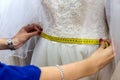 Female hands with measuring tape and wedding dress.