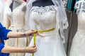 Female hands with measuring tape and wedding dress