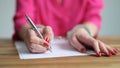 Female hands in metal handcuffs writing explanatory note closeup