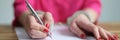 Female hands in metal handcuffs writing explanatory note closeup