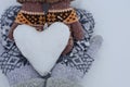 Female hands in mittens and baby hands in mittens keep the heart out of the snow against the background of white snow Royalty Free Stock Photo