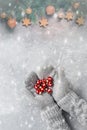 Female hands in mittens hold red Christmas balls, the border of the spruce branch is decorated with gold balls and stars. Top view Royalty Free Stock Photo