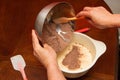 Female hands mix cocoa with dough on a wooden kitchen table. Making cake at home Royalty Free Stock Photo