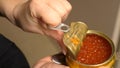 Female hands open metal can with red caviar Royalty Free Stock Photo