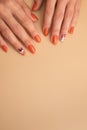 Female hands with orange manicure with a pattern under a glossy top