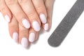 Female hands with overgrown nails white color with a nail file. Regrowth shellac or gel polish manicure need in correction
