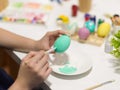 Female hands painting Easter eggs with poster colour on the table