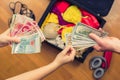 Female hands with passport Asian money and American hundred dollar bills. Suitcase with things on the floor. Choosing and exchange Royalty Free Stock Photo