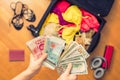 Female hands with passport Asian money and American hundred dollar bills. Suitcase with things on the floor. Choosing and exchange Royalty Free Stock Photo