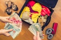 Female hands with passport Asian money and American hundred dollar bills. Suitcase with things on the floor. Choosing and exchange Royalty Free Stock Photo