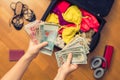 Female hands with passport Asian money and American hundred dollar bills. Suitcase with things on the floor. Choosing and exchange Royalty Free Stock Photo