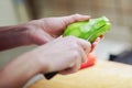 Female hands peel and cut fresh organic avocado with knife in kitchen. Red bell pepper on background. Royalty Free Stock Photo