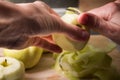 Female hands peeling skin off of green apple using a paring knife Royalty Free Stock Photo