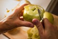 Female hands peeling skin off of green apple using a paring knife Royalty Free Stock Photo