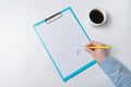 Female hands with pen on document and Cup of coffee. Woman puts signature on paper Royalty Free Stock Photo