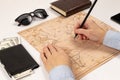 Female hands with a pencil show the place on the world map. on a white wooden table lie a wallet with money, sunglasses and Royalty Free Stock Photo