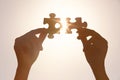 Female hands with pieces of puzzle and shining sun on background Royalty Free Stock Photo