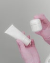 Female hands in pink gloves hold bottles for cream. Container for body lotion, toiletries. Tube for professional care Royalty Free Stock Photo