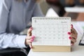 Female hands with pink manicure holding looseleaf paper calendar closeup Royalty Free Stock Photo