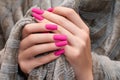 Female hands with pink nail design. Mate pink nail polish manicure. Female model hands with beige fluffy fabric