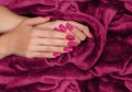 Female hands with pink nail design. Mate pink nail polish manicure. Female model hands on pink fluffy fabric