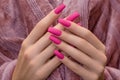 Female hands with pink nail design. Mate pink nail polish manicure. Female model hands hold purple fluffy fabric