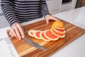 Wooden chopping board with sliced red grapefruit and knife. Royalty Free Stock Photo