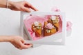 Female hands placing windowed lid on a box with thick slices of honey cake