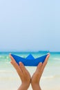 Female hands playing with blue paper boat on the beach Royalty Free Stock Photo