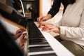 Female hands playing grand piano under the guidance of music teacher. Close-up fingers touch ebony and ivory piano keys Royalty Free Stock Photo