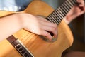 Female hands pluck the strings and fretboard of a yellow acoustic guitar, close up view